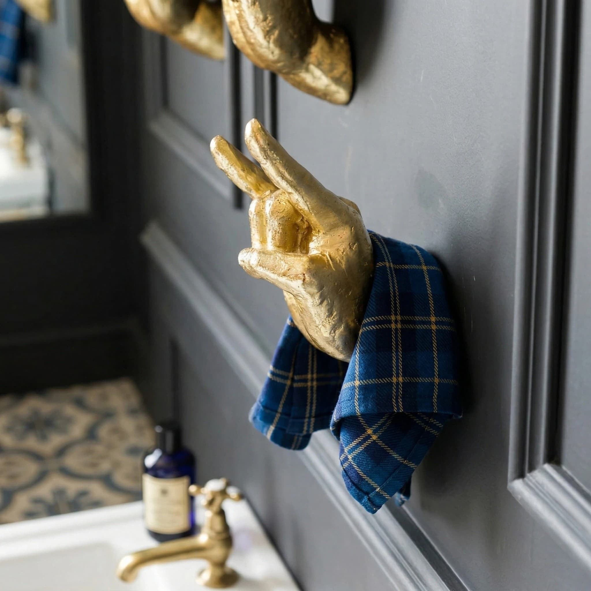 Gold wall hand hook holding a towel