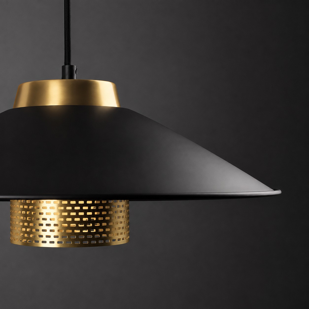 Close angled view of the matte black conical shade and brass center structure